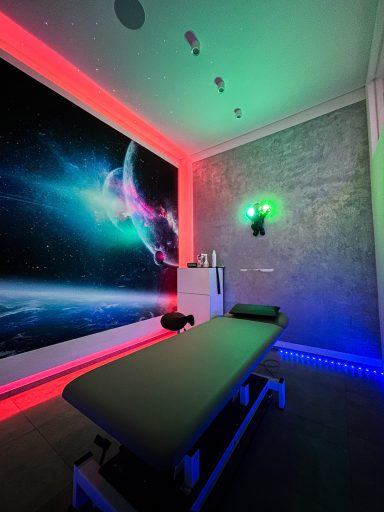 Behandlungsraum mit futuristischer Beleuchtung und Weltraumwandgestaltung.