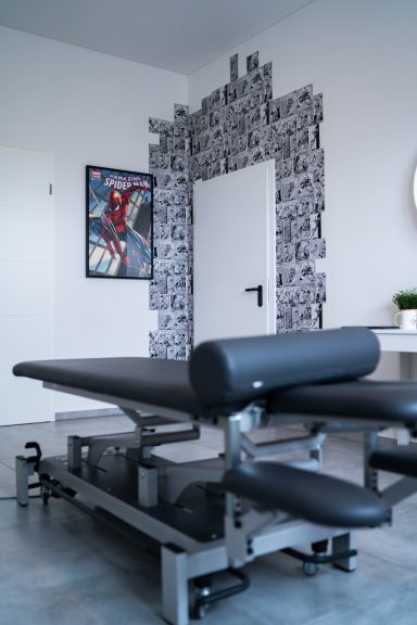 Behandlungsliege in einem modernen Raum mit einer Kunstwand und einer Tür.