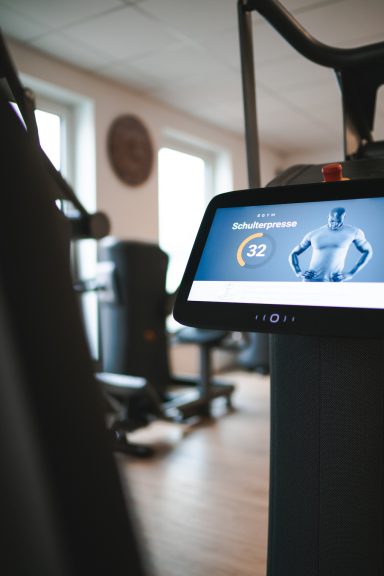 Fitnessgerät mit Bildschirm, der Trainingsdaten zeigt, in einem Fitnessstudio.